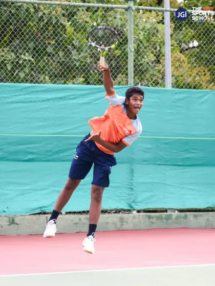 A young tennis player executes a powerful serve, capturing the explosive energy and technical precision we instill in our athletes through our high-performance tennis program.