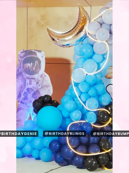 A detail shot of the crescent moon balloon and astronaut cutout, illuminated by cool blue and purple lighting.