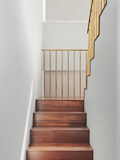 We believe even functional elements can be art. This dog-legged staircase, crafted from rich teak wood and accented with brass, is a sculptural centerpiece that also cleverly incorporates hidden storage, demonstrating our focus on integrated and thoughtful design.