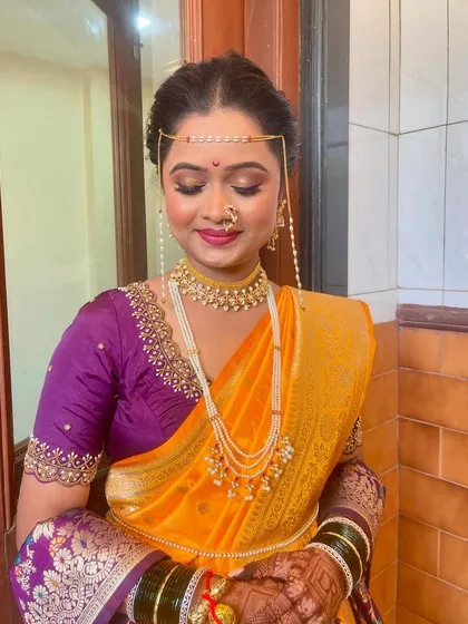A closer look at the bride's makeup, featuring soft pink eyeshadow and a matching lip color that complements her yellow and purple saree.