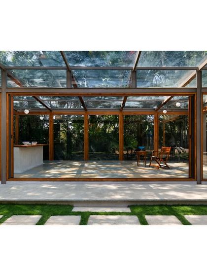 The pavilion's sliding glass doors open completely, removing any barrier between the interior space and the garden path.