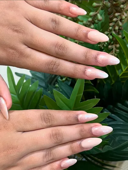A beautiful set of long, almond-shaped nails with a soft, pearlescent pink polish.