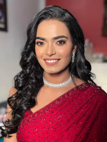 Radiant in red. This stunning look features a classic red saree paired with glamorous makeup and Hollywood waves.