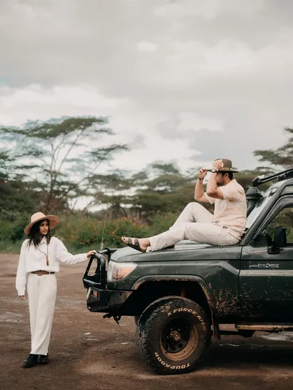 A stylish, adventurous portrait of Nikita and Harshil with their safari vehicle. This shot has an editorial feel, like a still from a classic adventure movie.