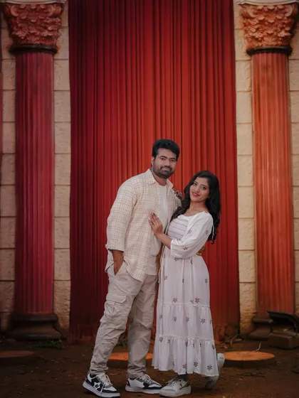 A couple poses against a backdrop of red pillars and curtains, creating a bold and dramatic effect.