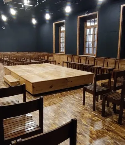 The empty Black Box Theatre, showcasing the beautiful restored wooden flooring and the contrast with the dark, acoustically treated walls.