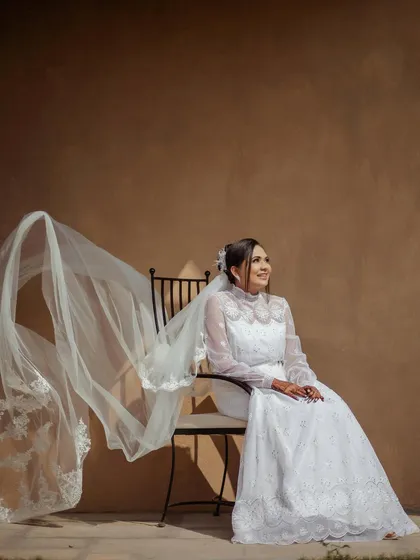 A bride in her beautiful white wedding gown, her long, embroidered veil flowing in the breeze. A picture of pure grace and elegance.