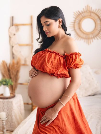 I love capturing the beauty of the bare baby bump. This mom-to-be wore a lovely two-piece orange outfit in my boho studio setup, creating a warm, natural, and absolutely stunning portrait.