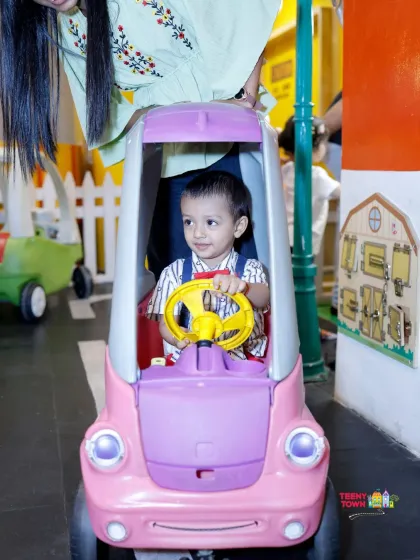 Beep beep! A little one enjoying a ride in one of our toy cars. Our play area has a mini-road for kids to cruise around.