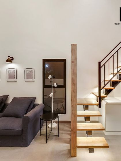 The living area of the 550 sq. ft. loft home, showing the staircase leading to the mezzanine and the comfortable seating area.