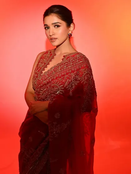 Radiant in red. This look is all about classic elegance, with a beautifully embroidered red saree complemented by a clean, glowing base and a simple updo.