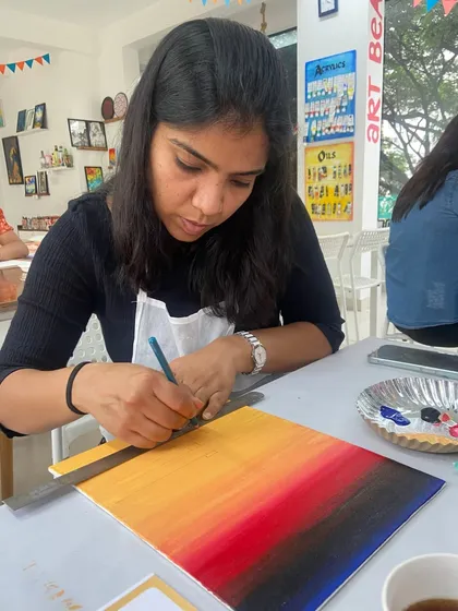 A participant carefully measures and paints a sunset gradient on her canvas. I teach simple techniques to achieve professional-looking results.