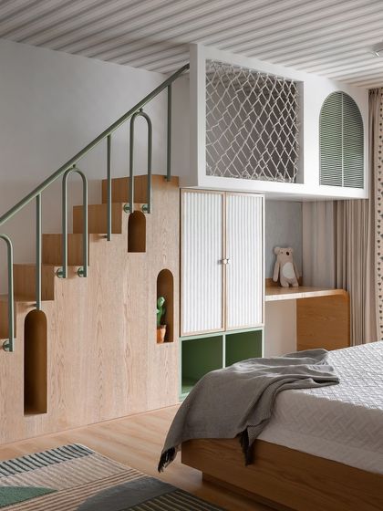 This playful kids' bedroom features a custom-built loft bed with a staircase that includes unique storage nooks. The green metal railing and reeded cabinet doors add color and texture.