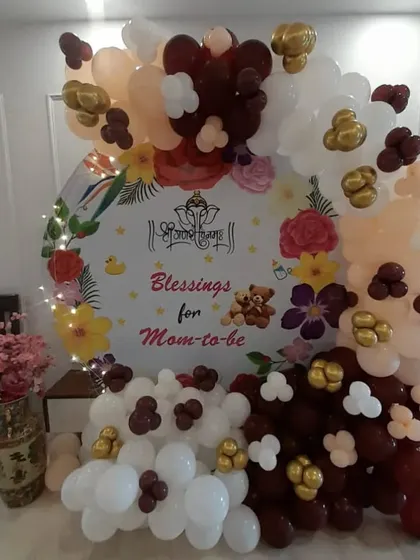 A traditional "Blessings for Mom-to-be" baby shower with a divine touch. The backdrop includes a Ganesha motif and is surrounded by a warm-toned balloon arrangement.