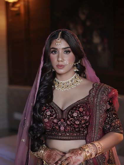 A close-up of the bridal makeup. The look features a subtle contour and warm tones on the eyes to complement the deep maroon of her outfit.