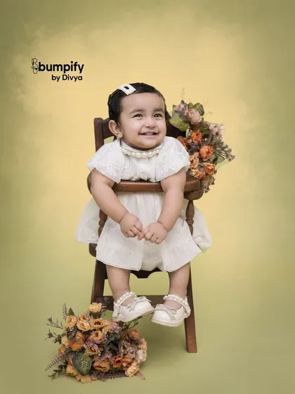A sweet, smiling portrait. The simple, elegant styling with the vintage chair and flowers allows the child's personality to shine.