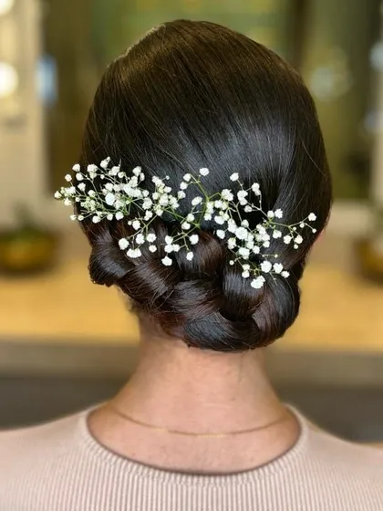 A meticulously crafted low bun, interwoven with a braid and adorned with baby's breath. This is the epitome of springtime chic and elegance.