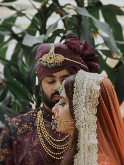 An intimate close-up where the couple's faces are close, eyes closed in a moment of serene connection. The rich colors of their outfits and the groom's turban add to the royal feel of this portrait.