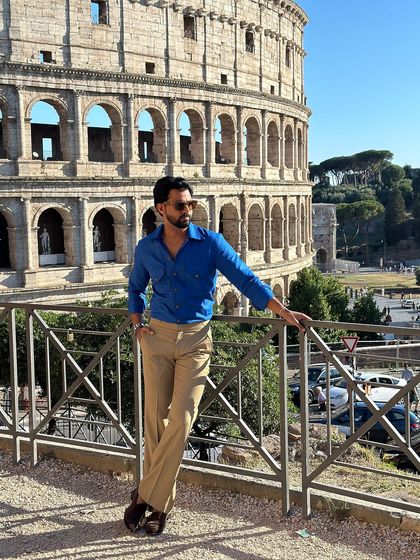 The royal blue Viaggio shirt offers a pop of color against the historic backdrop, creating a memorable travel photo.
