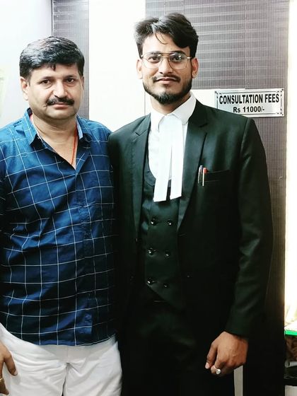 With a client or senior colleague in my office. The sign "Consultation Fees" is visible, indicating a professional setting.