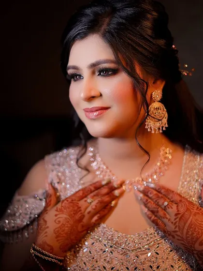 A beautiful portrait of the bride admiring her necklace. This shot focuses on the intricate details of her jewelry and henna.