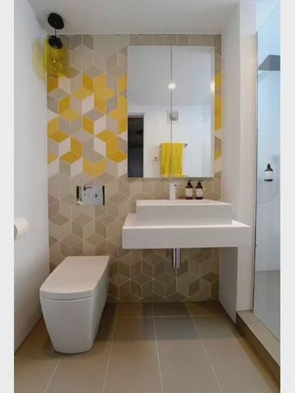 This compact bathroom uses a bold geometric tile accent wall to add personality. A floating toilet and wall-mounted sink are excellent choices for maximizing floor space.