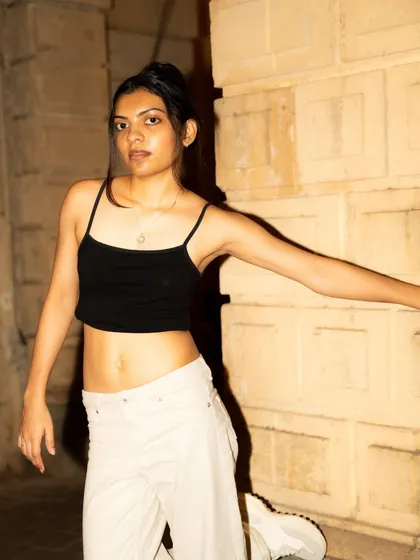 A playful, dynamic pose against a stone wall at night. The flash freezes the motion, creating a crisp and energetic portrait.