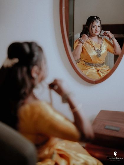 The bride adjusting her necklace while looking in the mirror, a candid getting-ready shot from her engagement.