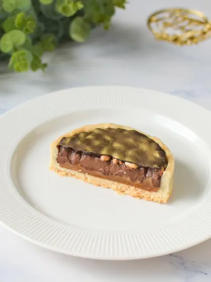 A slice of the Snickers Caramel Tart, which is featured in my Rakhi Delight Box. It has a buttery crust, a layer of caramel and peanuts, and a rich chocolate ganache topping.