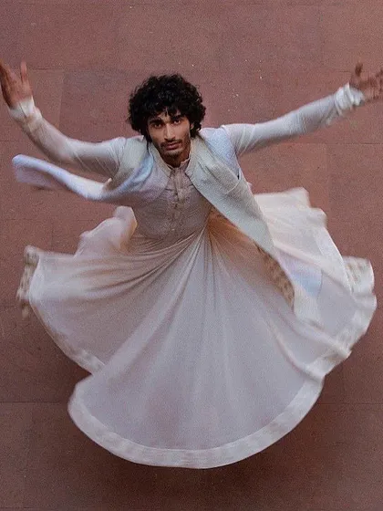 Capturing movement and grace, this aerial shot of a model in a flowing white angrakha kurta demonstrates a blend of traditional form and contemporary artistry.