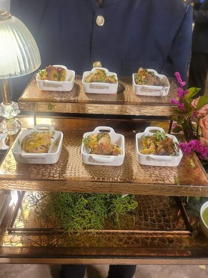 A tiered tray presenting individual portions of Chicken Kebab, served with a side of fresh green chutney. This setup allows for elegant and easy service during a bustling event.