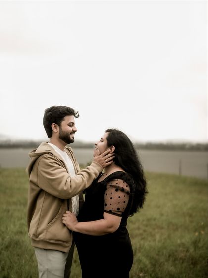A tender moment between the couple. He gently holds her face as they gaze at each other, a simple gesture full of love and affection.