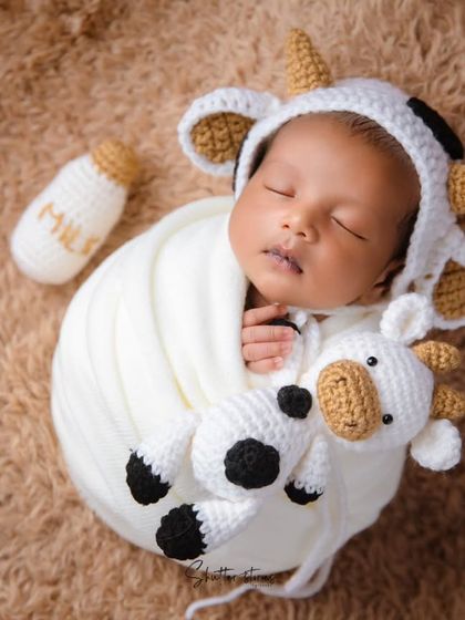 An overhead shot of the full cow-themed setup, showing the baby, plushie, and milk bottle.