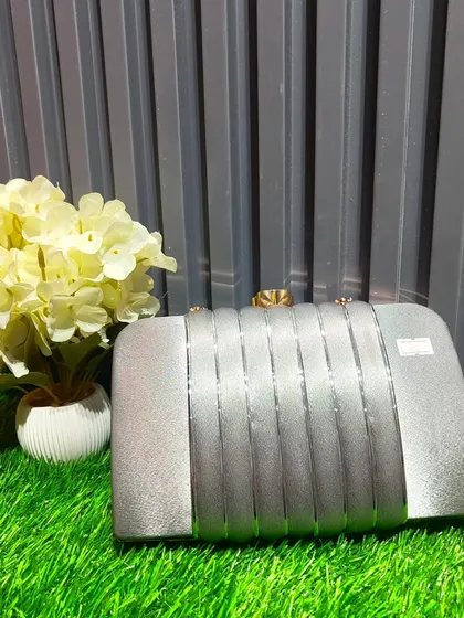A sleek silver hard-case clutch. Its minimalist design makes it a versatile accessory that can be paired with almost any colorful outfit.
