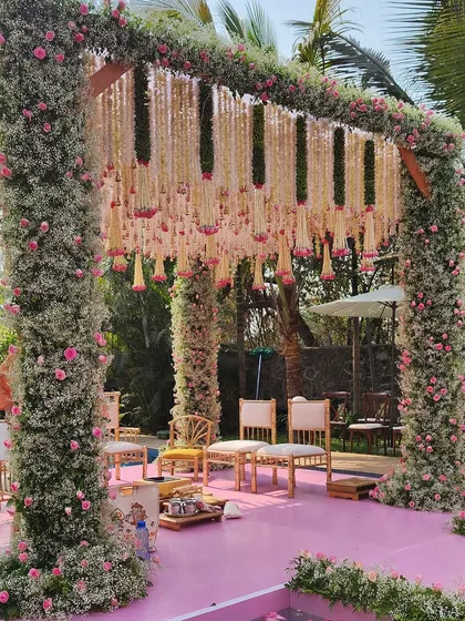 A poolside mandap in Alibaug, with pillars covered in baby's breath and pink roses, and a delicate floral ceiling. The pink aisle is set over the pool for a unique touch.