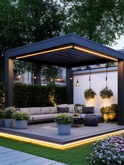 A modern, freestanding pergola with integrated LED lighting along its top frame. The structure defines a sophisticated lounge area on a raised deck, complete with contemporary furniture and planters.