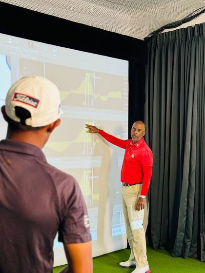 Using data to mentor a player. Here, I am breaking down swing analytics on screen, translating complex numbers into clear, understandable feedback that the athlete can immediately apply to their training.