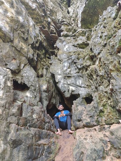 A trekker sitting inside a small cavity in the cave wall, a perfect spot for a photo.