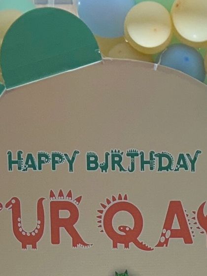 A custom "Happy Birthday" sign with a dinosaur-themed font for Furqan's party. Personalization is key to making each event feel special.