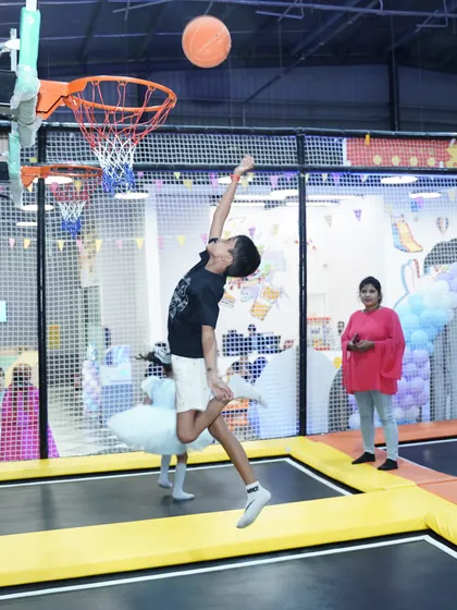 A young boy shows off his skills, getting some serious air to make a basket on our trampoline court. It's one of our most popular and interactive games.