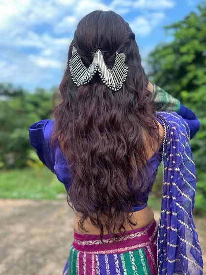 Getting ready for Garba night. This half-up hairstyle features soft waves and a statement silver accessory, designed to stay in place while looking festive and beautiful through every dandiya twirl.