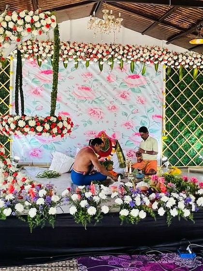A behind-the-scenes look at the setup for a naming ceremony. This image shows the floral arch and cradle being prepared, highlighting the fresh materials and careful craftsmanship involved.
