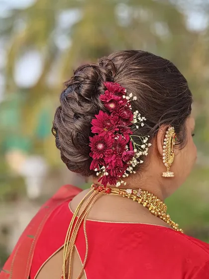 A detailed view of the bridal bun, or 'khopa', adorned with beautiful deep red flowers, complementing her saree.