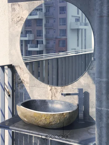An example of integrating raw, natural elements into an urban setting. This hand carved stone sink on a balcony provides a functional feature while adding an earthy, organic texture that contrasts with the city view reflected in the mirror.