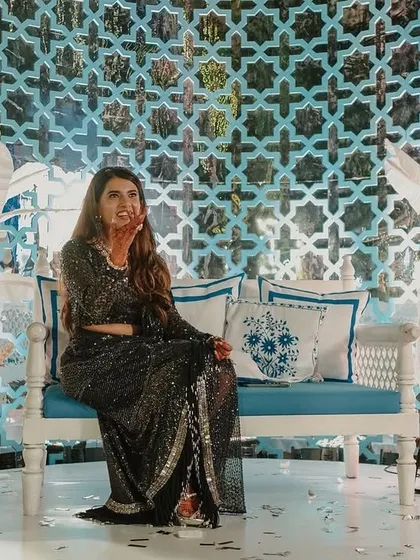 The bride, Yasha, at her Bar Palladio-inspired Haldi. The backdrop features a custom-cut 'jaali' screen and handcrafted sholawood flowers, all in a beautiful blue and white palette.