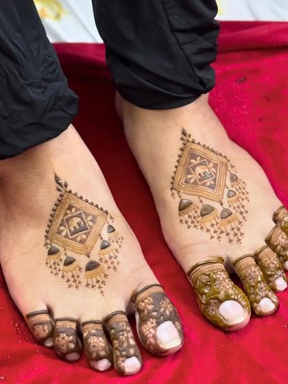 A unique, jewelry-like design for the feet. This minimalist mehandi features a central motif with hanging bells, connected to detailed patterns on the toes.