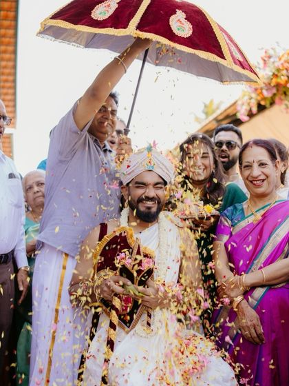 The groom's Kashi Yatra ritual, where he is welcomed by his family. The shower of petals adds a dynamic and celebratory feel to this traditional moment.