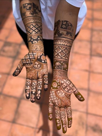 A top-down view of the engagement mehendi, showing the elephant bands on the forearms and the personalized symbols on the palms.