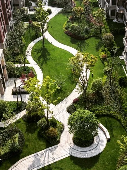 An aerial view of a large-scale commercial or residential landscape project. The design features meandering pathways, circular lawns, and strategically placed trees to create a park-like environment.
