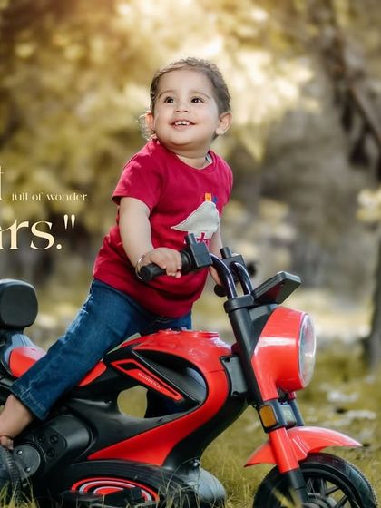 Heart full of wonder, eyes full of stars. A happy girl in a red shirt enjoys a ride on her toy motorcycle.